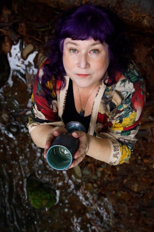 Paula holding a cup looking upwards.